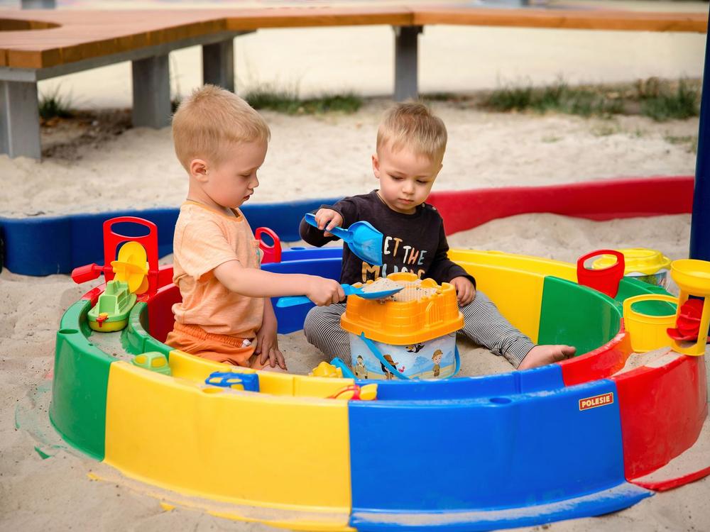 Zwei Kleinkinder spielen zusammen im Sandkasten