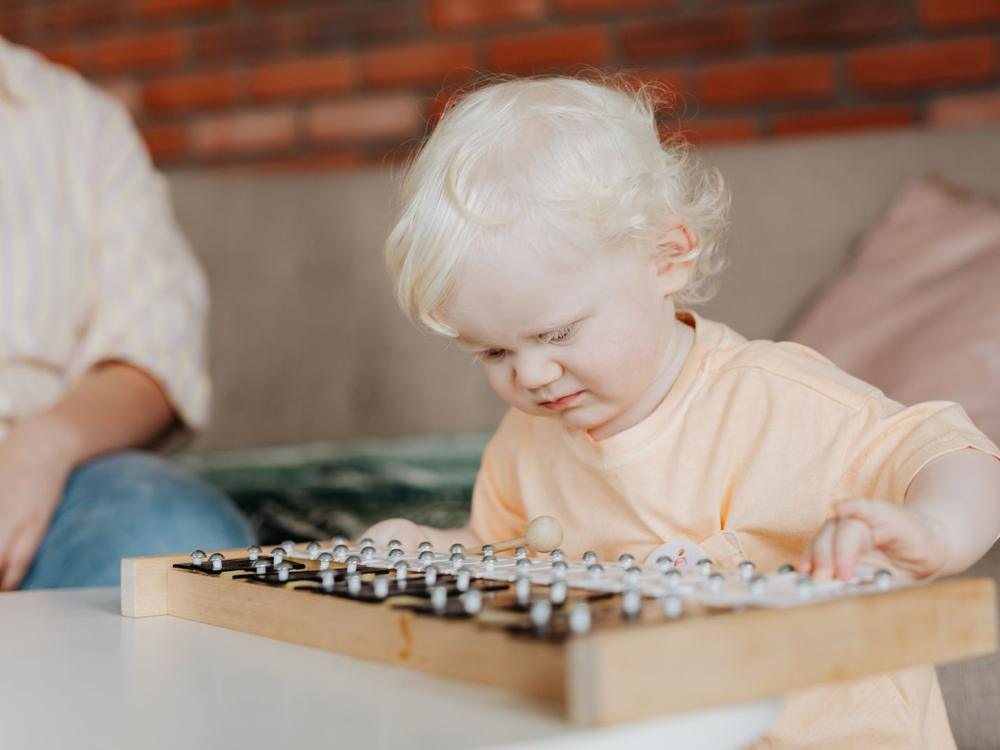 Kleinkind spielt konzentriert auf einem Holz-Musikinstrument